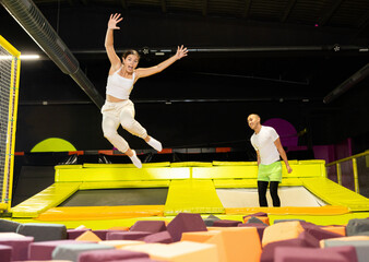 Happy athletes, man and girl, training to jump on trampolines at the trampoline center