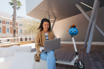 Young Asian female student using a laptop in front of the university
