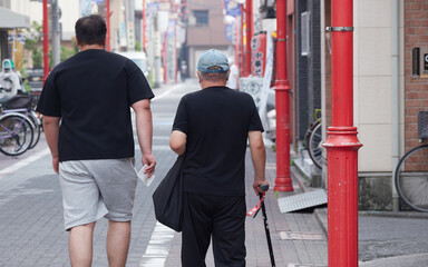 Obraz premium 夏の都市の商店街で歩くシニア男性の姿