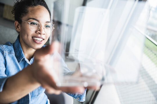 Young businesswoman examining object at work place