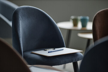 Empty chair with clipboard and pen resting on seat in counseling session setting, blurred...