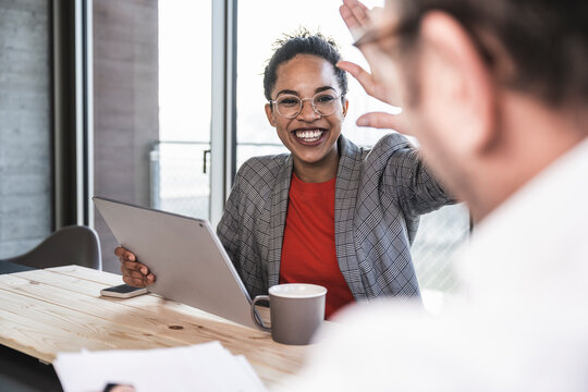 Cheerful businesswoman giving high-five to colleague in office