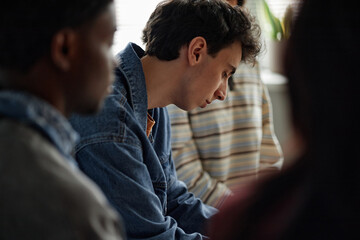 Multiethnic group of teenagers sitting together during counseling session, Caucasian teenage boy in...