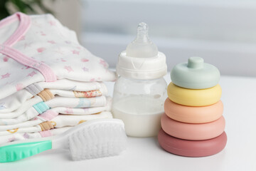 Baby clothes with bottle, toy rings and brush. Baby care.