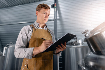 Young caucasian male brewer conducting quality checks in modern brewery