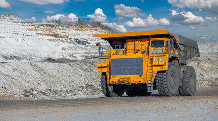 Massive mining dump truck work on open coal mine during, winter sunny day