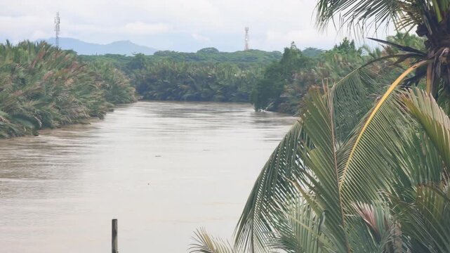 A real-life footage of a flood caused by a river overflowing its banks, affecting homes and streets in the surrounding area. The water level continues to rise as the heavy rainfall leads to uncontroll