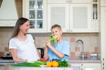 Mother and son preparing corn and vegetables in home kitchen