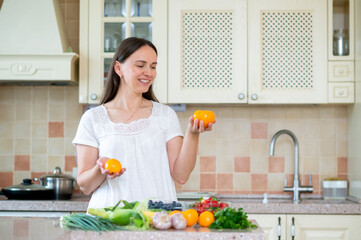 Woman holding orange tomatoes with fresh vegetables in cozy kitchen