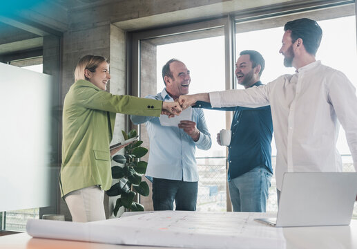 Happy business colleagues fist bumping at table