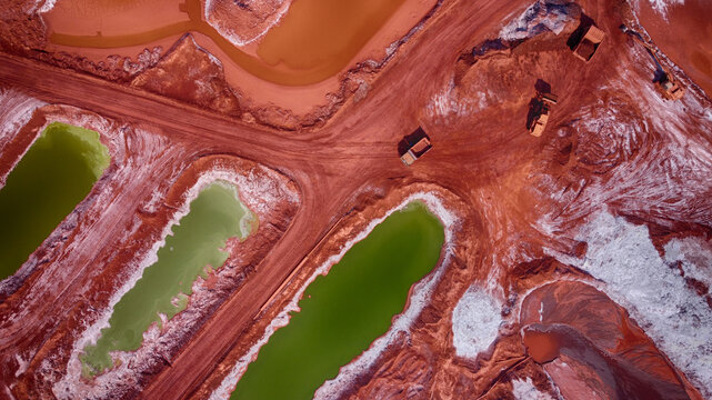Aerial view of vivid green pools contrasting with the red earth and heavy machinery at Mykolaiv Alumina Plant, Mykolaiv, Mykolaiv Oblast, Ukraine.
