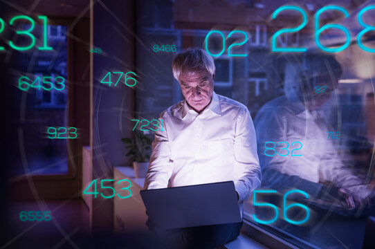 Futuristic numbers moving towards senior businessman working on laptop in office