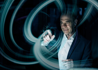 Digital composite image of businessman creating swirl pattern on graphical user interface