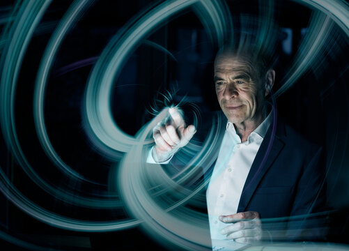 Digital composite image of businessman creating swirl pattern on graphical user interface