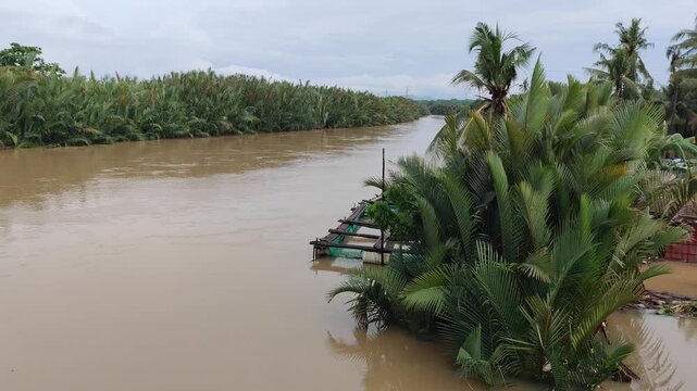 A real-life footage of a flood caused by a river overflowing its banks, affecting homes and streets in the surrounding area. The water level continues to rise as the heavy rainfall leads to uncontroll