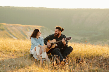 A loving couple enjoys a beautiful romantic moment together, playing acoustic guitar in a vibrant and sunlit landscape