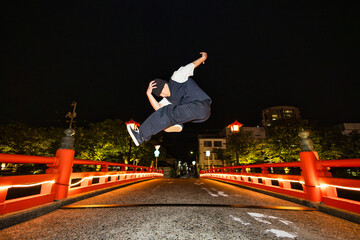 ライトアップされた和風の橋でブレイクダンスジャンプを披露する若い男性