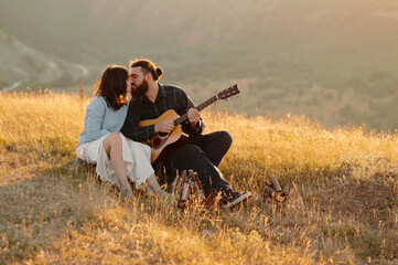 A loving couple enjoys a beautiful romantic moment as they play guitar together in a serene sunset landscape