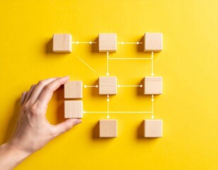 Hand Connecting Wooden Blocks to Form a Network Diagram on Yellow Background
