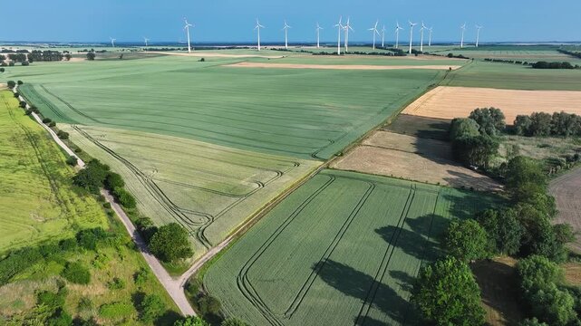 Aerial view of lush green and golden fields, punctuated by the presence of wind turbines under a clear blue sky, Brussow, Brandenburg, Germany.