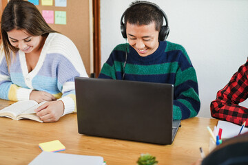 Multiracial students using laptop computer and reading books while studying together at school library - Back to school and technology concept - Focus on asian boy head