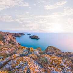 stony coast of the sea bay under a blue cloudy sky at the sunset