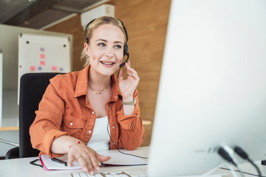 Smiling businesswoman wearing headset and having video conference