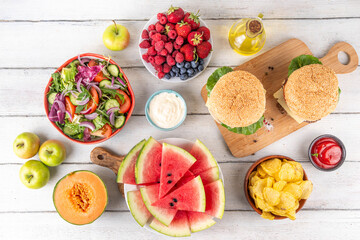 Tasty summer barbecue table with hamburgers, salads, fruits and snacks