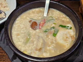 Traditional Korean fermented soybean stew (Cheonggukjang) served in a hot stone bowl, with tofu, green onions, mushrooms, and chili peppers.