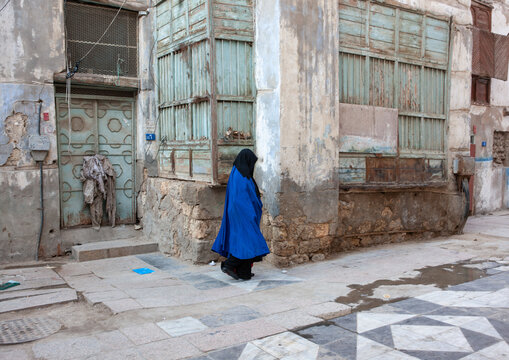 Saudi woman in abaya walking in a street in the old quarter, Hijaz Tihamah region, Jeddah, Saudi Arabia