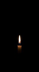 Single candle on dark background with soft glow