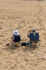Couple assis sur des chaises de plage, profitant d'un moment de détente au bord de la mer.