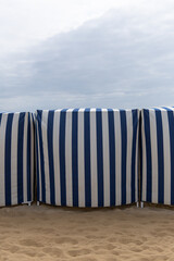 Tentes de plage rayées en bord de mer sous un ciel nuageux à l'aube.