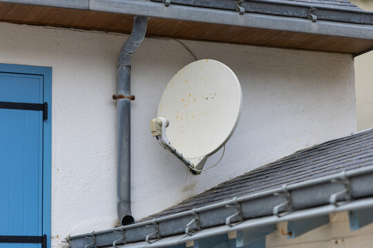 Installation d'une antenne parabolique sur le mur d'une maison &agrave; la campagne en milieu urbain.