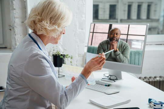 Mature doctor consulting patient through video call