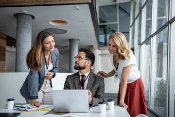 Business team collaborating on project using laptop in modern office