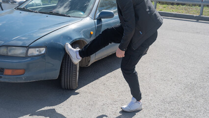 Caucasian man examines and tries to fix a deformation on the body of his car. 