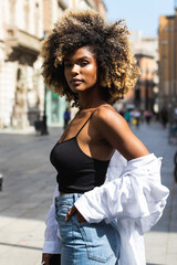 Serious black woman with curly hair on street