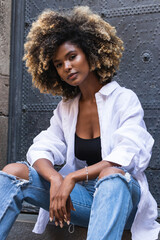 Attractive dark skinned millennial girl looking at camera. African American woman dressed in casual attire, feels confident and healthy.