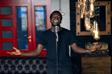 Handsome attractive african american singer, man singing in retro microphone in studio music recording