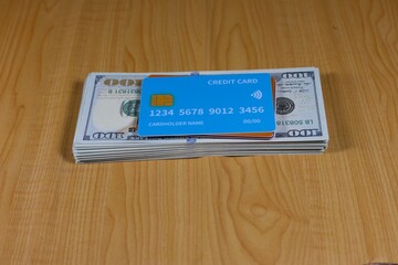The credit card is on top of a stack of US dollar bills.