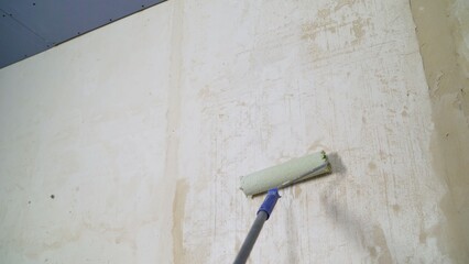 Construction worker applying primer on wall using paint roller