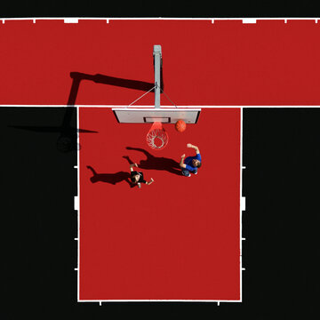 Aerial view of the vivid red basketball court, contrasting with the stark black surroundings, showcasing players in action, Split, Split-Dalmatia County, Croatia.