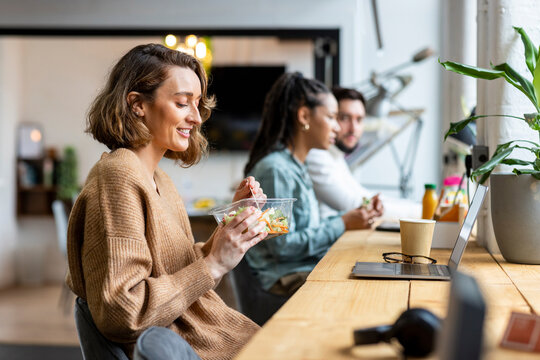 Smiling businesswoman eating salad in lunch break in office