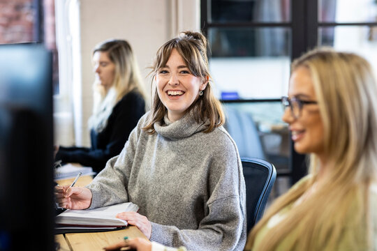 Happy businesswoman with note pad sitting at desk