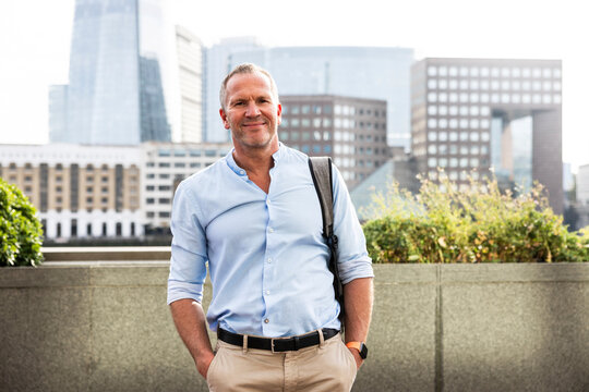 Smiling businessman standing with hands in pockets at London, UK