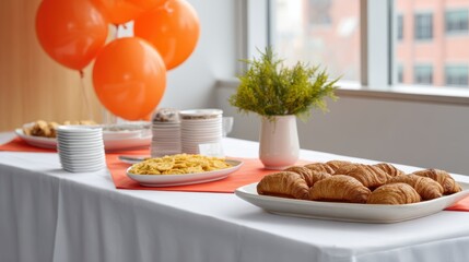 Table setup with refreshments, snacks, and congratulatory banners at office party