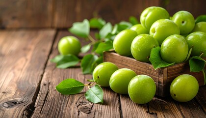 Wooden crate overflowing with vibrant green plums and leaves, on a rustic wooden surface