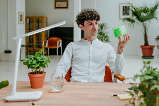 Smiling businessman examining cube maze at desk in office