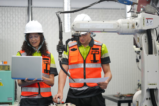 Smart Latino engineer working on AI technology in robotics electronics engineering laboratory. Hispanic students' research project is programming robot machine with intelligent mechanical control